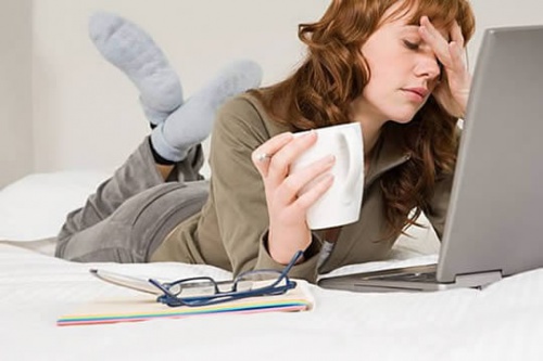 Ragazza stanca sdraiata davanti al portatile