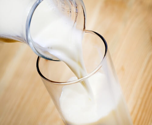 latte versato da una caraffa a un bicchiere