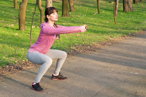 ragazza esegue squat nel parco