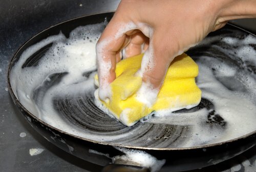 donna pulisce padelle con Coca-Cola