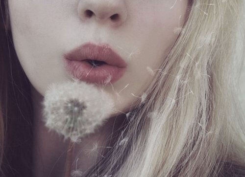 ragazza senza pesi soffia petali di un dente di leone