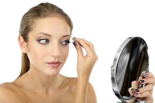 ragazza allo specchio depila le sopracciglia
