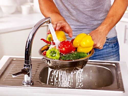 uomo lava la verdura sotto il rubinetto