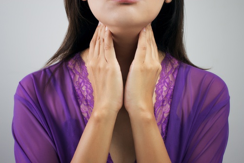 donna con mani sul collo tiroide