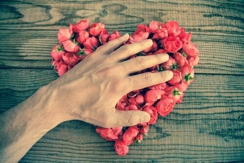 mano che tocca un cuore di rose amare