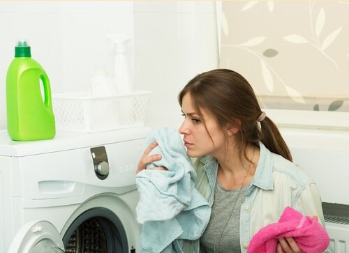 donna che odora un asciugamano appena uscito dalla lavatrice ammorbidenti