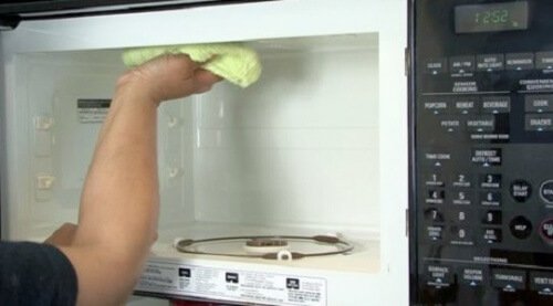 mano che pulisce un formo a microonde cucina