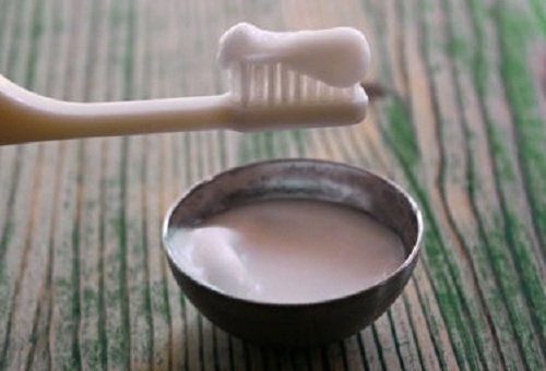 Spazzolino e ciotola con dentifricio preparato in casa