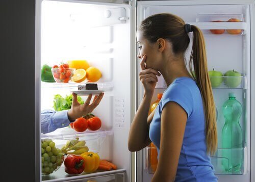 Donna cerca cibo in frigo