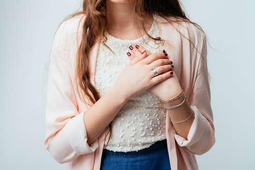 ragazza giovane si tiene la mano sul cuore