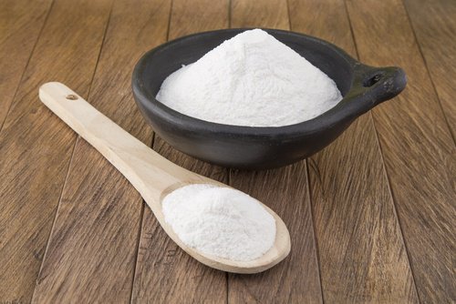 Bicarbonato di sodio dentro una ciotola e in un cucchiaio di legno
