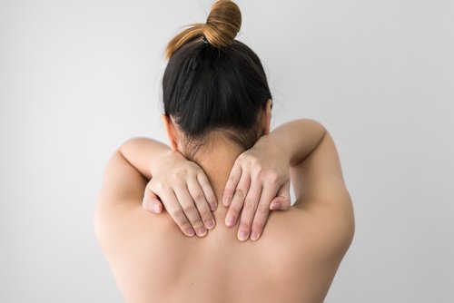 donna di spalle si massaggia la schiena