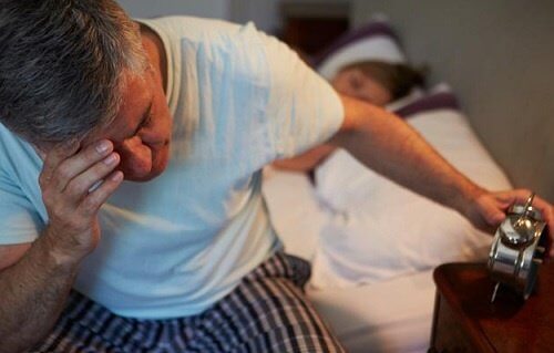 Uomo che soffre di insonnia guarda la sveglia