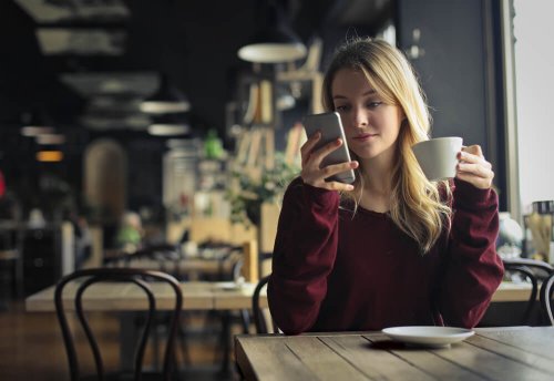 Ragazza beve un caffè e guarda il cellulare