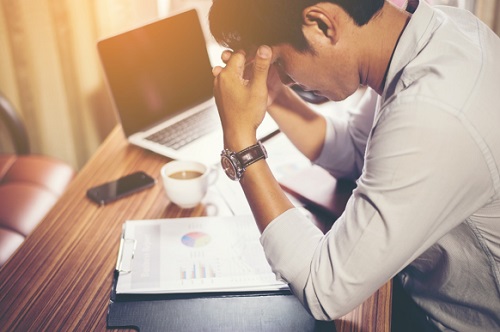 uomo che lavora al pc con mal di testa