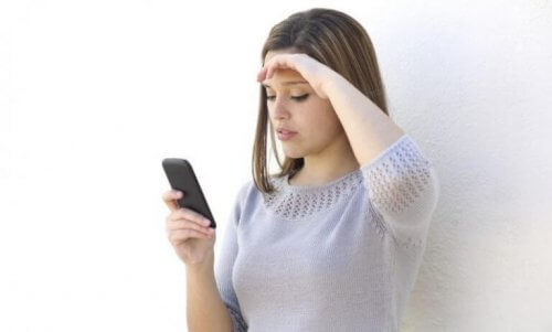 Ragazza con cellulare e mano sulla fronte