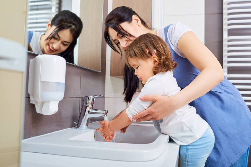 Mamma che fa lavare le mani alla figlia.