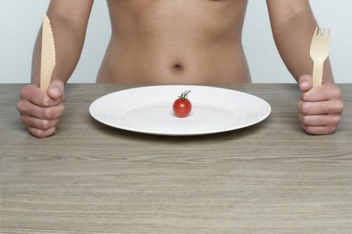 persona con posate in mano e piatto con un solo pomodorino