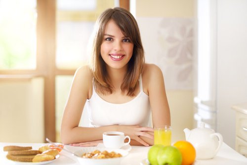 ragazza sorridente a tavola con alimenti per prima colazione