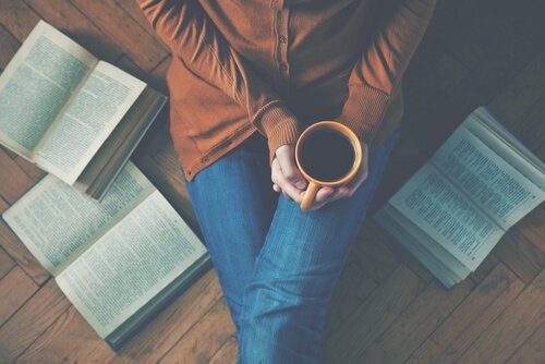 Donna seduta sul pavimento con un caffè e dei libri