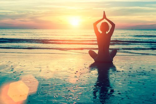 Donna che fa yoga in riva al mare