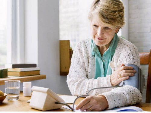 Signora che si misura pressione arteriosa in casa.