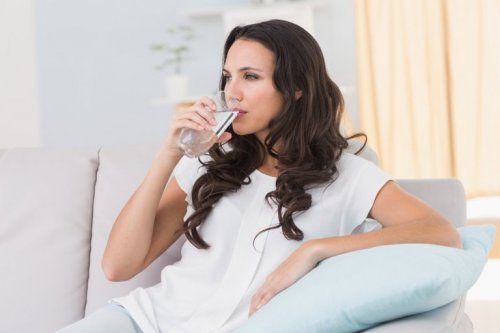 donna seduta sul divano beve acqua