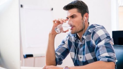 Ragazzo al computer che beve acqua