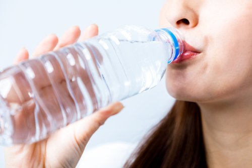 ragazza beve acqua da bottiglia di plastica