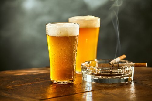 Bicchiere di birra e posacenere con sigaretta