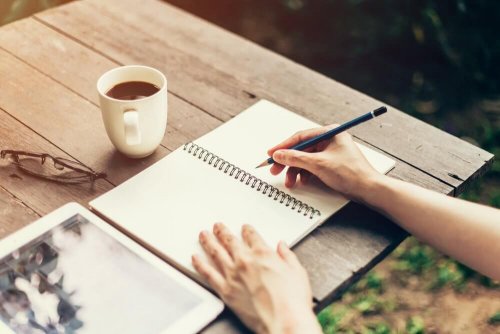 Donna che scrive con quaderno e tazza di caffè