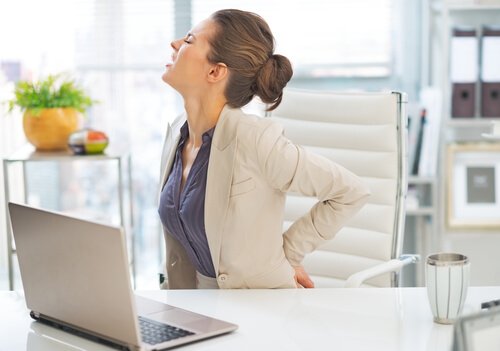 Donna di fronte al computer con dolore alla schiena