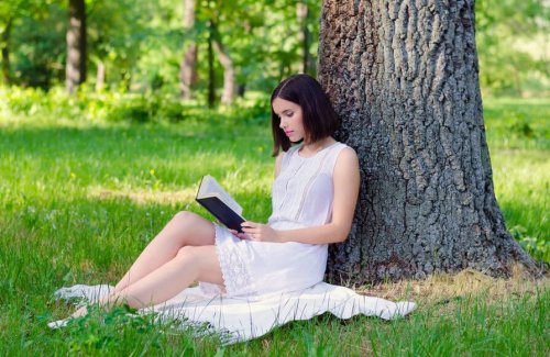 Donna che legge un libro sotto un albero
