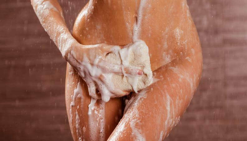 Igiene intima: donna si insapona sotto la doccia.