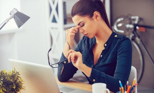 Donna davanti al pc con mano sulle tempie