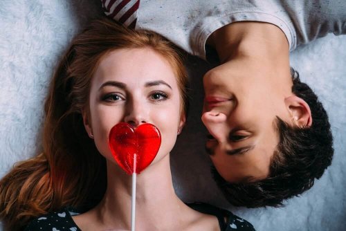 Coppia sorridente con lecca lecca a forma di cuore