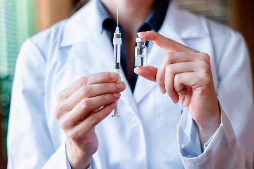 medico con siringa e boccetta di liquido
