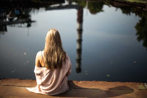 Ragazza seduta davanti a lago