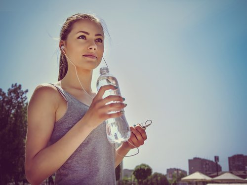 Ragazza con cuffie e bottiglia acqua