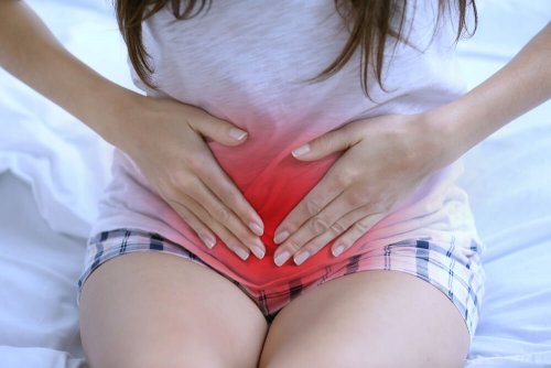 Anomalie del ciclo mestruale - Donna seduta sul letto con mal di pancia