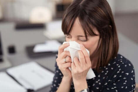 Propoli contro i sintomi di raffreddore e influenza: donna che si soffia il naso.