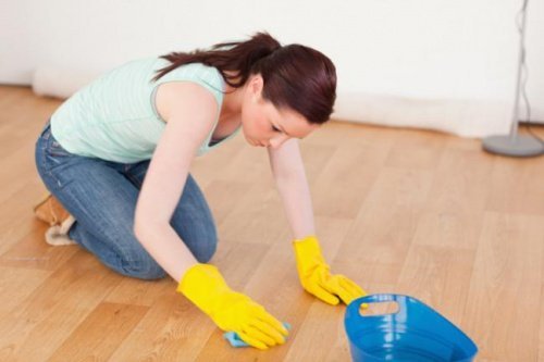 Donna con guanti cerca di eliminare graffi dal pavimento 