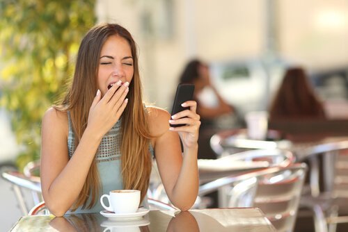 Ragazza che sbadiglia seduta ad un tavolo con caffè