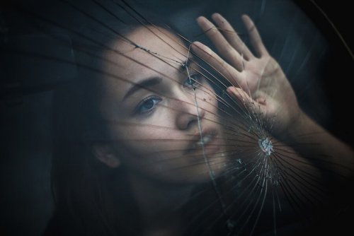 Donna con mano appoggiata su vetro rotto