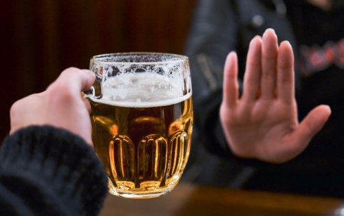 persona dice no con la mano a bicchiere di birra