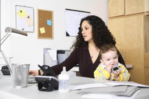 Mamma che lavora mentre tiene il suo bambino essere una super mamma