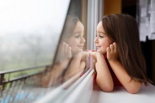 Bambina guarda fuori dalla finestra.