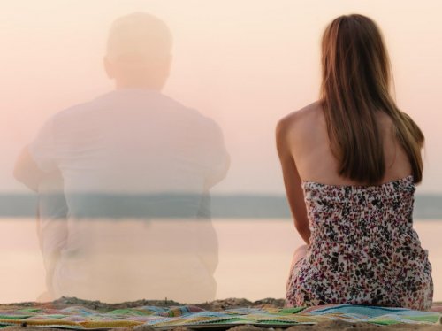 donna seduta al mare e ombra trasparente di uomo al suo fianco