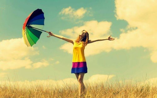 Ragazza in campagna con vestito e ombrello colorati