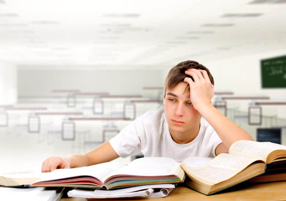 Adolescente esausto davanti ai libri